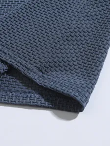 Close-up of textured stretch fabric and hem stitching on men's navy blue Polo shirt