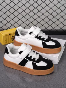 Vista detallada de zapatillas infantiles en blanco y negro con suela de goma y velcro