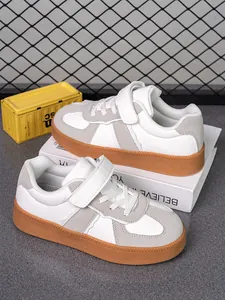 Primer plano de zapatillas blancas y grises para niños con suela de goma marrón duradera