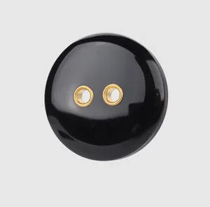Detailed macro view of a glossy black resin button featuring elegant gold-rimmed holes