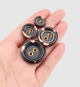 Detailed view of high-end resin buttons with marble pattern and gold eyelets on a hand