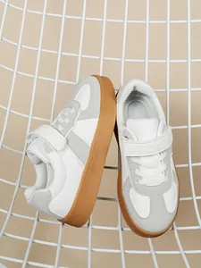 Vista detallada de las zapatillas blancas para niños con suela de goma y velcro.