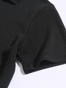 Macro detail of men's black textured polo shirt showing high-quality waffle knit fabric