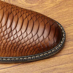 Close-up detail of brown men's dress shoe featuring an embossed snakeskin scale texture.