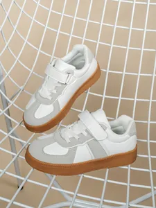 Detalle de zapatillas infantiles blancas y grises con suelas de goma marrón suaves