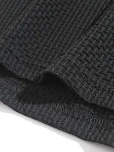 Close-up of black textured waffle knit fabric and hem on men's sport polo shirt.