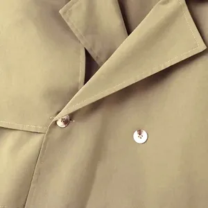Detaillierte Nahaufnahme eines beigen Herren-Trenchcoats mit Reverskragen und Knöpfen.