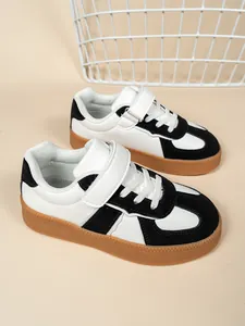 Vista detallada de zapatillas infantiles en blanco y negro con velcro y suela goma