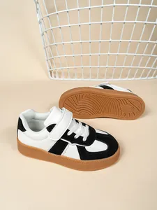 Detalle de zapatillas infantiles en blanco y negro con suelas de goma marrón antideslizantes.