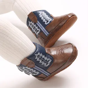Dettaglio degli stivaletti da cowboy per neonati con ricami blu e marroni caldi