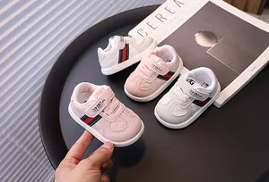 Close-up detail of pink and white baby walking sneakers with signature stripe design