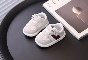 Close-up of white baby sneakers with quilted texture and red-green side stripe details.