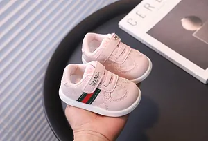 Close-up of pink infant walking shoes with green and red stripes and soft soles.