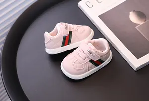 Macro view of pink quilted baby walking shoes featuring classic red and green web stripe details