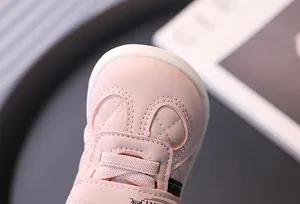 Macro view of pink baby walking shoes showing soft leather texture and stitch details