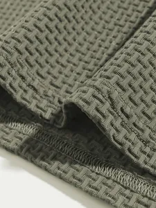 Macro detail of breathable olive green textured knit fabric and neat hem stitching