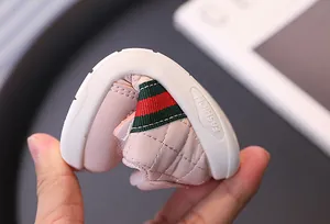 Close-up of pink flexible baby sneaker with soft sole showing extreme bending capability