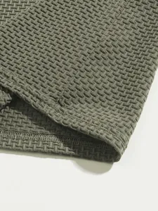 Close-up detail of olive green men's polo shirt showing textured waffle fabric and hem stitching