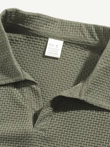 Macro close-up detail of a textured green polo shirt collar with an inner size and fabric tag