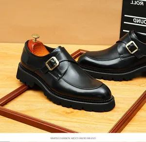 Close-up detail of black leather monk strap shoes with gold buckle and thick lug sole.