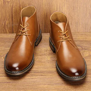 Close-up view of vintage brown leather men's desert boots on a rustic wood background texture