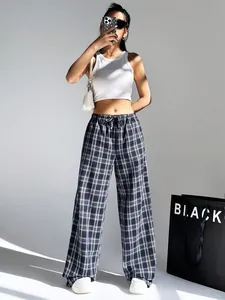 Elegant women's plaid wide-leg trousers styled with a white tank top in a studio shot.
