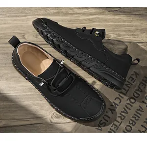 Gros plan de chaussures de conduite en cuir noir cousu main sur surface en bois.