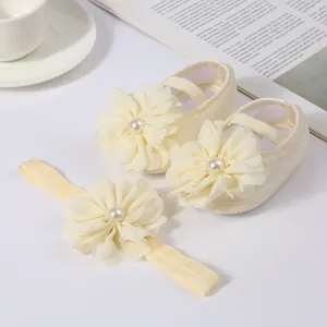 Détail rapproché de chaussures de bébé crème et d'un bandeau avec fleurs en mousseline