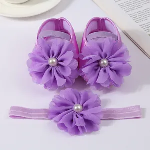 Gros plan sur l'ensemble chaussures et bandeau bébé violets avec fleurs en mousseline.