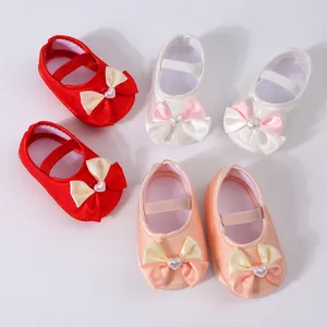 Top view of soft-sole baby princess shoes in red, white, and peach with bow details