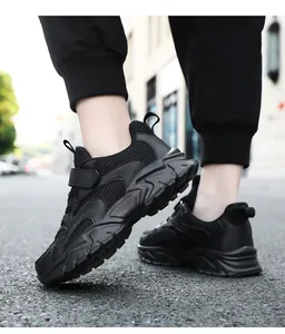 Detail view of black breathable mesh children's sneakers worn outdoors on asphalt