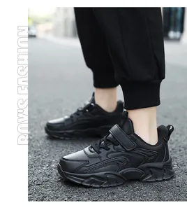 Side view detail of black boys athletic sneakers with hook and loop strap on road