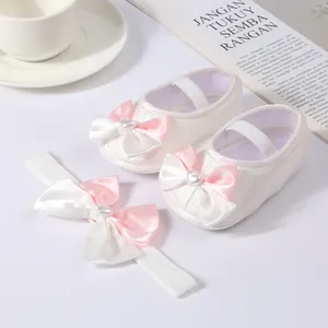 Close-up of white baby princess shoes and matching bow headband set for newborns
