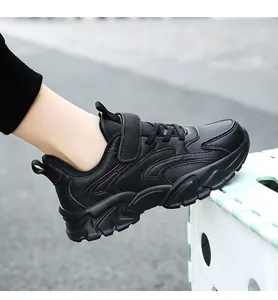 Side view of black children's athletic sneaker with Velcro strap and thick sole