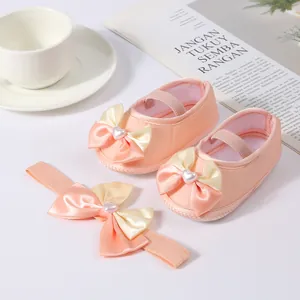Close-up of elegant pink baby princess shoes and matching bow headband gift set