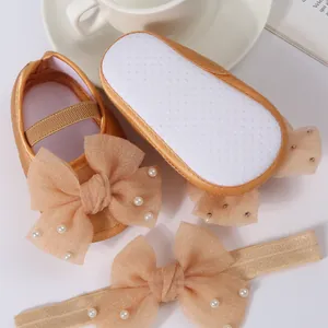 Close-up of champagne gold baby shoes and headband set with pearl bow detail