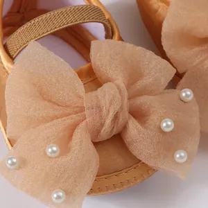 Detailed view of baby dress shoe featuring elegant mesh bow and pearl accents in champagne