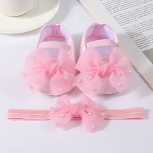 Detail of pink infant shoes and headband set with large mesh bows and pearls