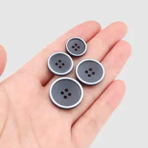 Set aus vier grauen Harzknöpfen mit Silberrand auf einer Handfläche zur Größenangabe