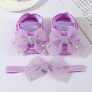 Macro detail of the purple infant shoe and headband set decorated with large mesh bows and pearls.