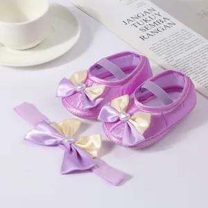 Close-up of elegant purple baby princess shoes and matching satin bow headband set