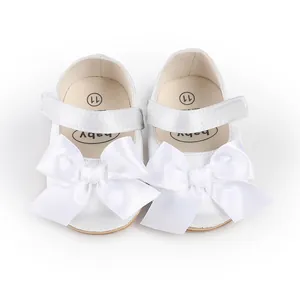 Detailed view of elegant white baby walking shoes featuring large satin bow decorations.