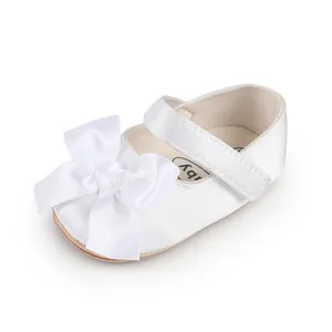 Detailed close-up of a white satin baby walker shoe with elegant bow decoration