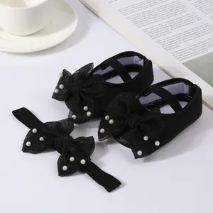 Detailed macro shot of black baby Mary Jane shoes with mesh bows and pearl headband