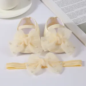 Detail of cream baby shoe and headband set with pearl mesh bows for christening