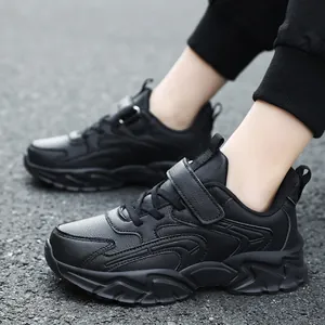 Durable black children's sports sneakers for boys and girls on outdoor asphalt background