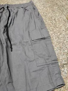 Dettaglio dei pantaloncini cargo grigi con tasca laterale e coulisse nera regolabile
