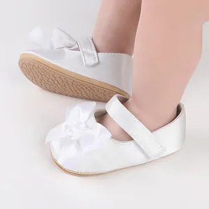 Detail showing the white satin bow and velcro strap of infant walking shoes