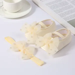 Macro view of cream baby shoes and headband set with elegant pearl mesh bows