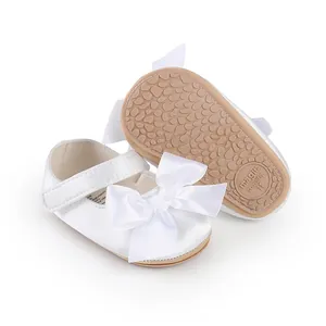 Detail of white baby pre-walker shoe with large bow and textured non-slip sole